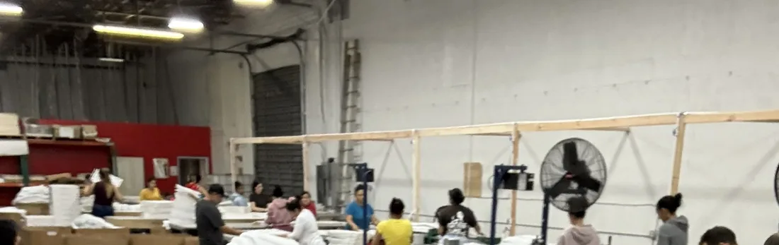 An assembly hall: rows of work benches with staff preparing and packing components.